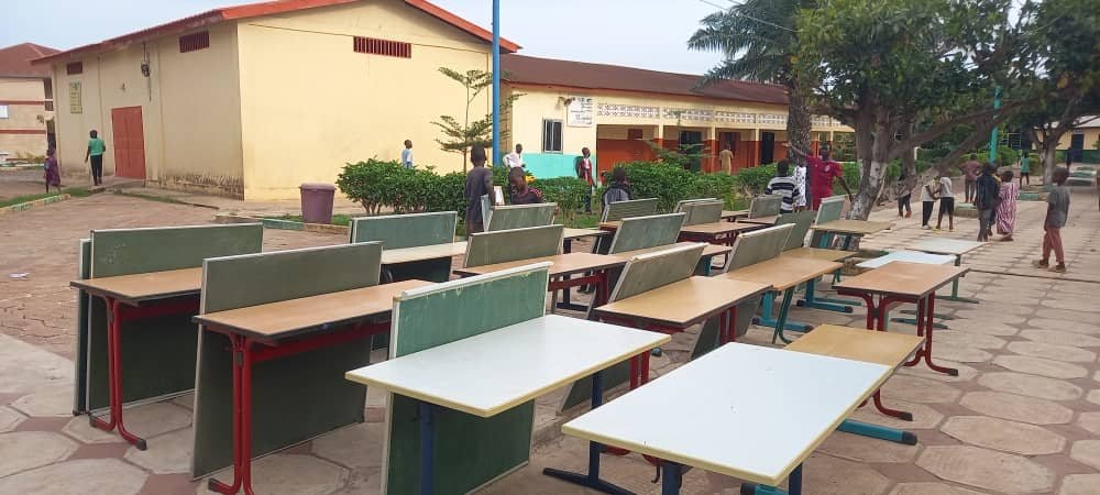 Mobilier scolaire prêt à être remis dans la cour d’une école en Guinée