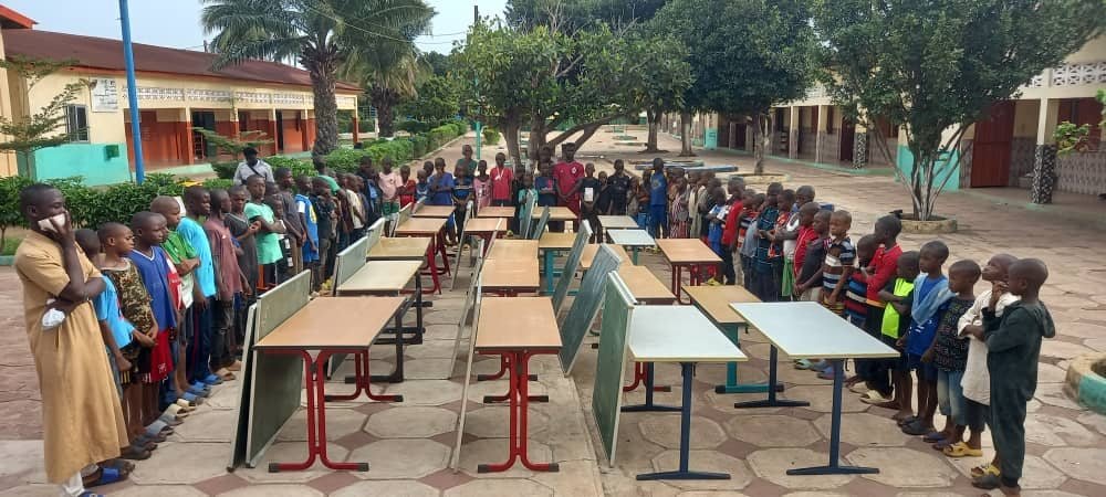 Des élèves entourent les tables et tableaux qui viennent d’être livrés
